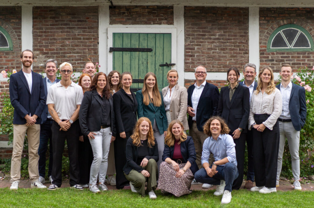 Das Beratungsteam von fjol, hier 18 Personen, steht gemeinsam vor einer roten Backsteinmauer.